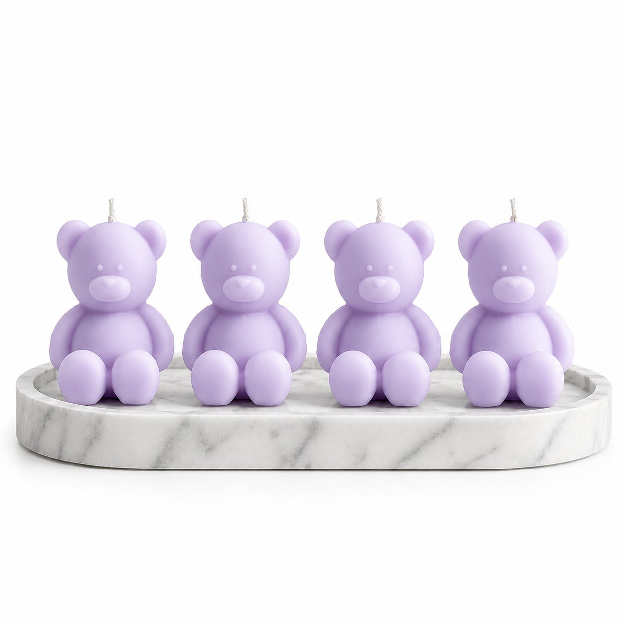 Four lavender teddy bear candles arranged on a round white marble tray against a plain white background.