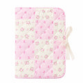 A charming quilted pencil case featuring a delicate pink and white patchwork design adorned with small floral and bow prints. The case closes securely with a lace tie bow on the side, combining a soft, feminine aesthetic with practical functionality for storing pens, pencils, markers, and other stationery essentials. - School Stationery | Asena Boutique Qatar