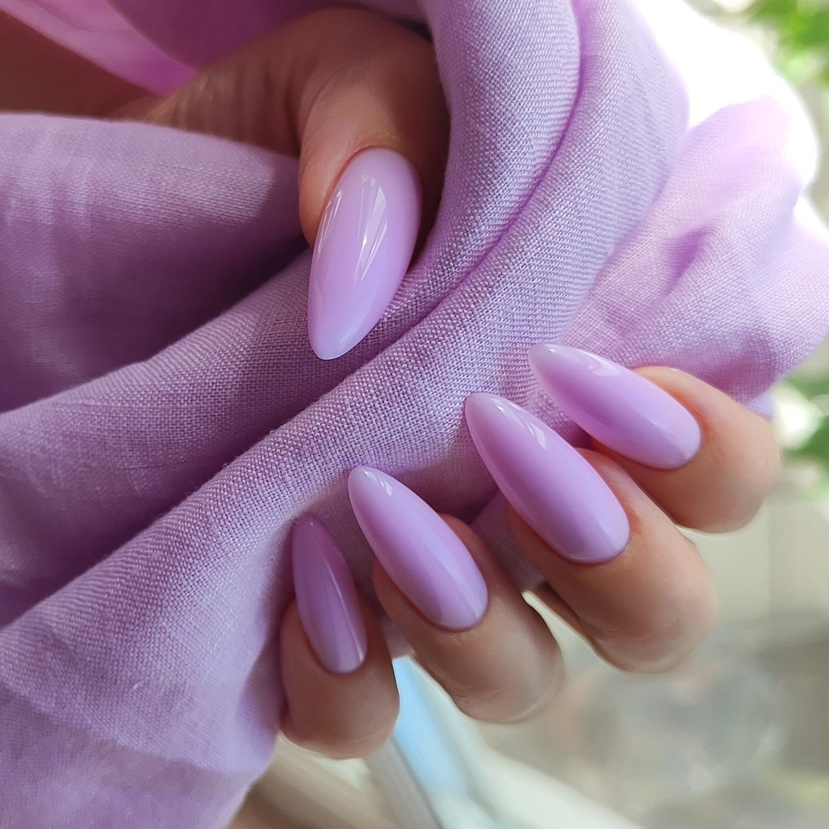 Lavender Serenity Nails - Press-On Nails | Asena Boutique Qatar
A close-up of manicured fingernails in a glossy pastel lavender shade, held against a soft lavender fabric backdrop.
